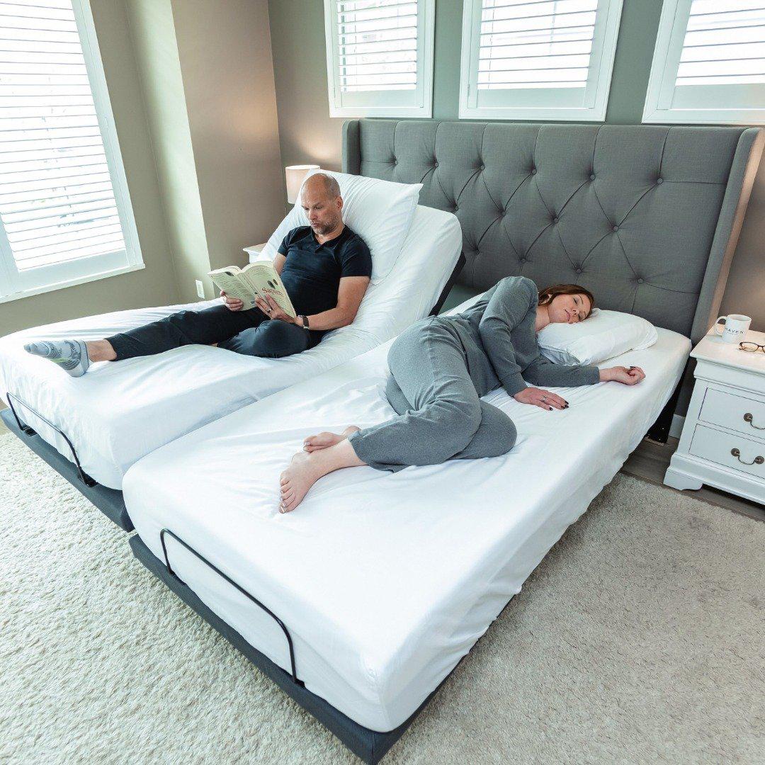 10 SPLIT KING_202105_split king_rejuvenate_adjustable_powerframe_bedframe_grey_middle age_ bri steve_side sleeper_side sleeper pillow_white sheets_white bedding_reading_working_book_ipad_couple-