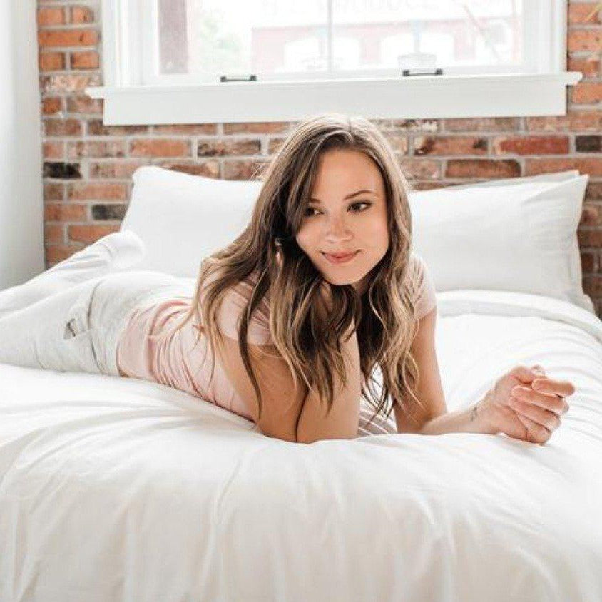 Woman in white laying across Haven Mattress with Starlight White bedding 